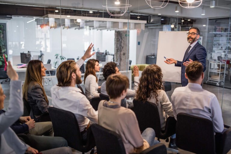 Participantes com a mão levantada durante treinamento corporativo